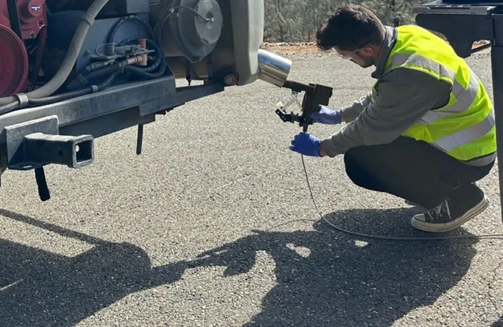 CARB-credentialed tester performing on-site emissions testing on a heavy-duty diesel truck at a Sacramento Region fleet yard